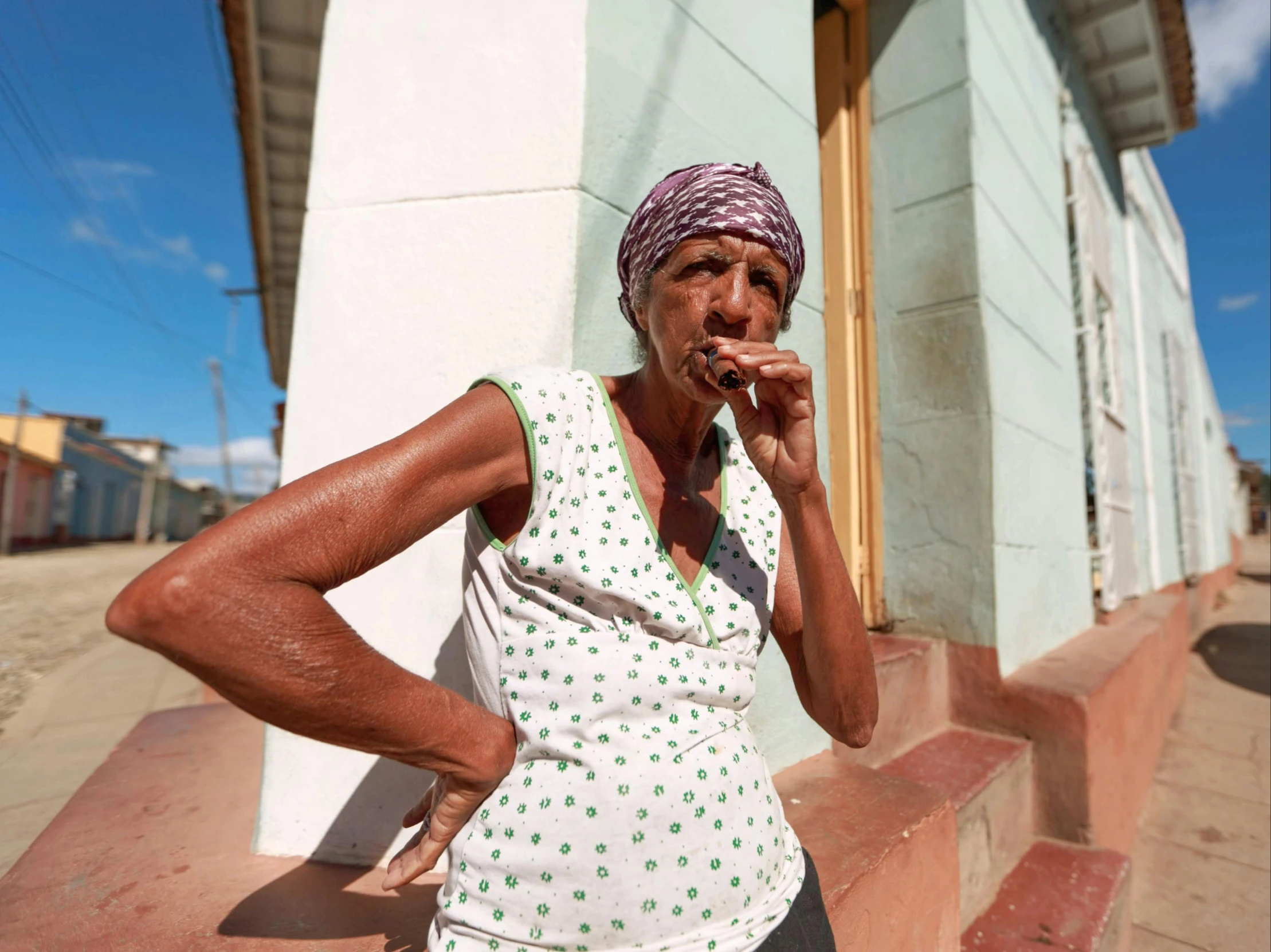 a woman talking on a cell phone in front of a building, pexels contest winner, hyperrealism, there is a cigar in his mouth, cuban setting, standing outside a house, an old lady with red skin