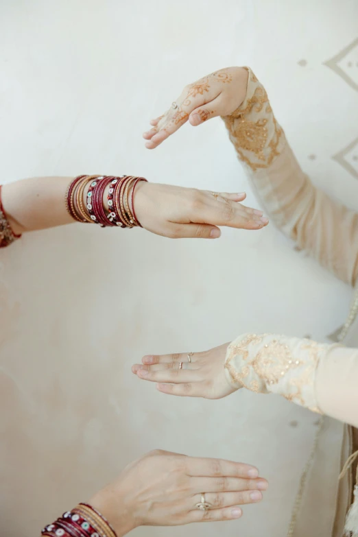 a couple of women standing next to each other, by Nina Hamnett, trending on unsplash, arabesque, bangles, maroon, wedding, reaching out to each other