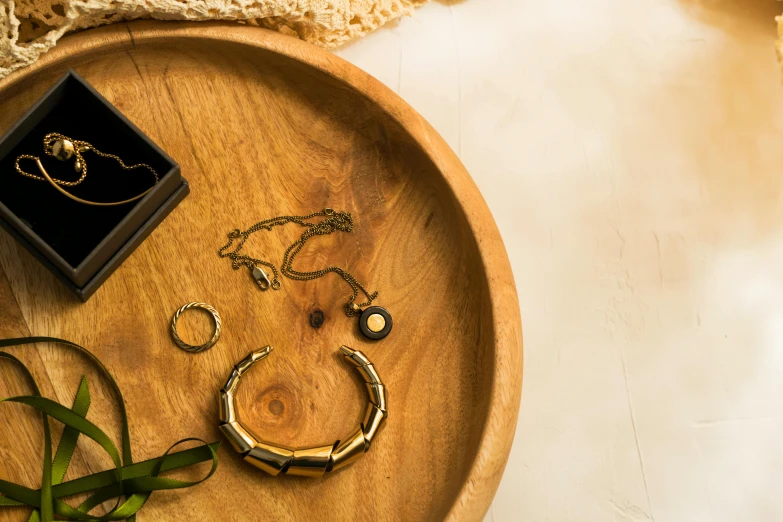 a wooden tray topped with jewelry on top of a table, a still life, inspired by Eden Box, trending on pexels, circle, golden collar, professional product shot, afternoon lighting