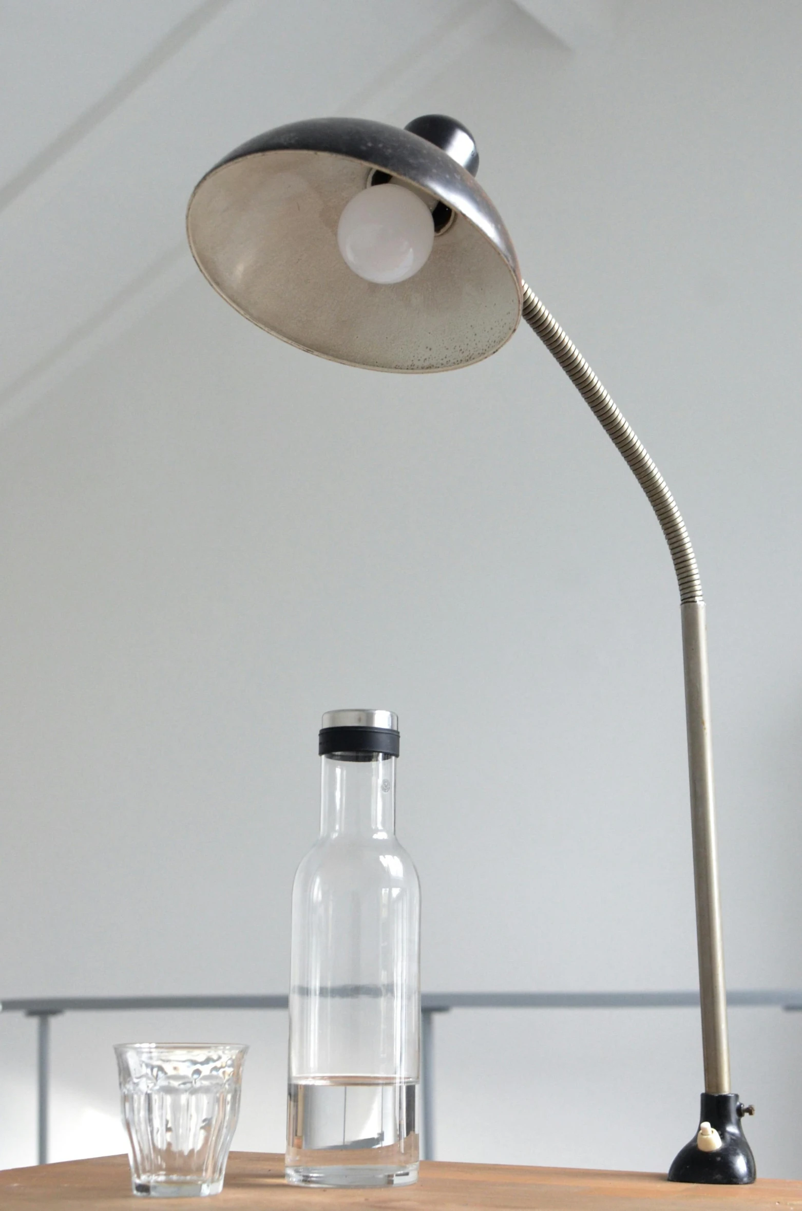 a lamp sitting on top of a wooden table next to a glass, an album cover, inspired by Constantin Hansen, minimalism, stainless steal, image apothecary, hoog detail, lamp ( ( ( gym ) ) ) )
