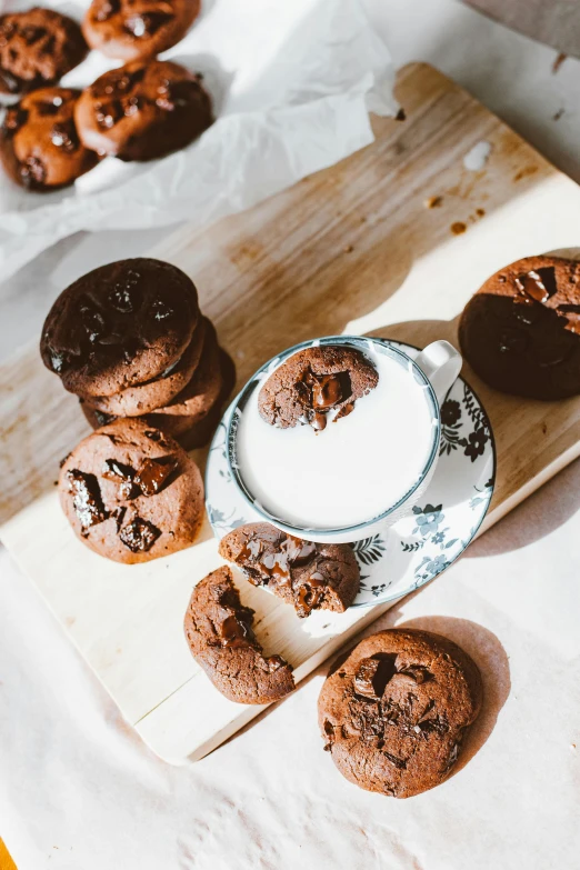 a wooden cutting board topped with chocolate cookies and a cup of milk, by Julia Pishtar, unsplash, modernism, lots of sunlight, wide high angle view, 15081959 21121991 01012000 4k, desserts