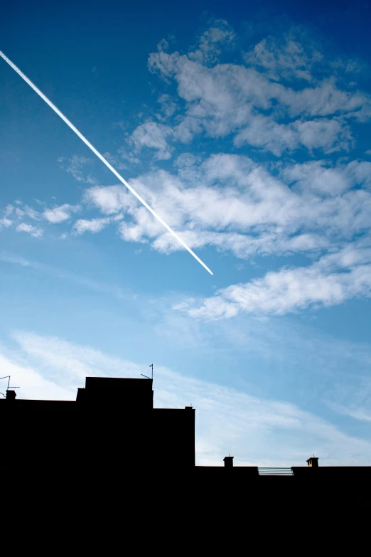 a jet flying through a blue sky over a city, by Peter Churcher, minimalism, contrails, as photograph
