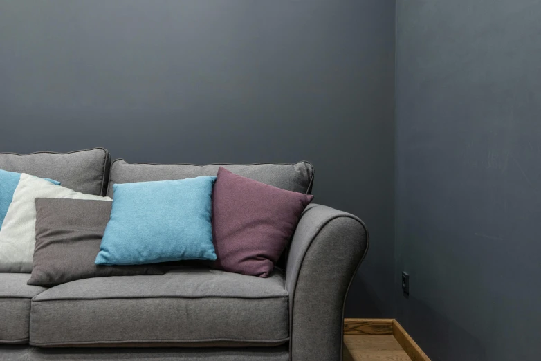 a couch that has some pillows on it, inspired by Thomas Struth, unsplash contest winner, photorealism, darkslategray wall, blue and purple scheme, wall corner, color ( sony a 7 r iv