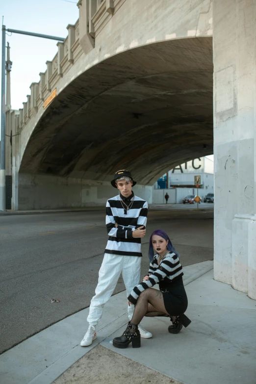 a couple of people standing next to each other on a sidewalk, graffiti, striped, bridges, mime, freeway