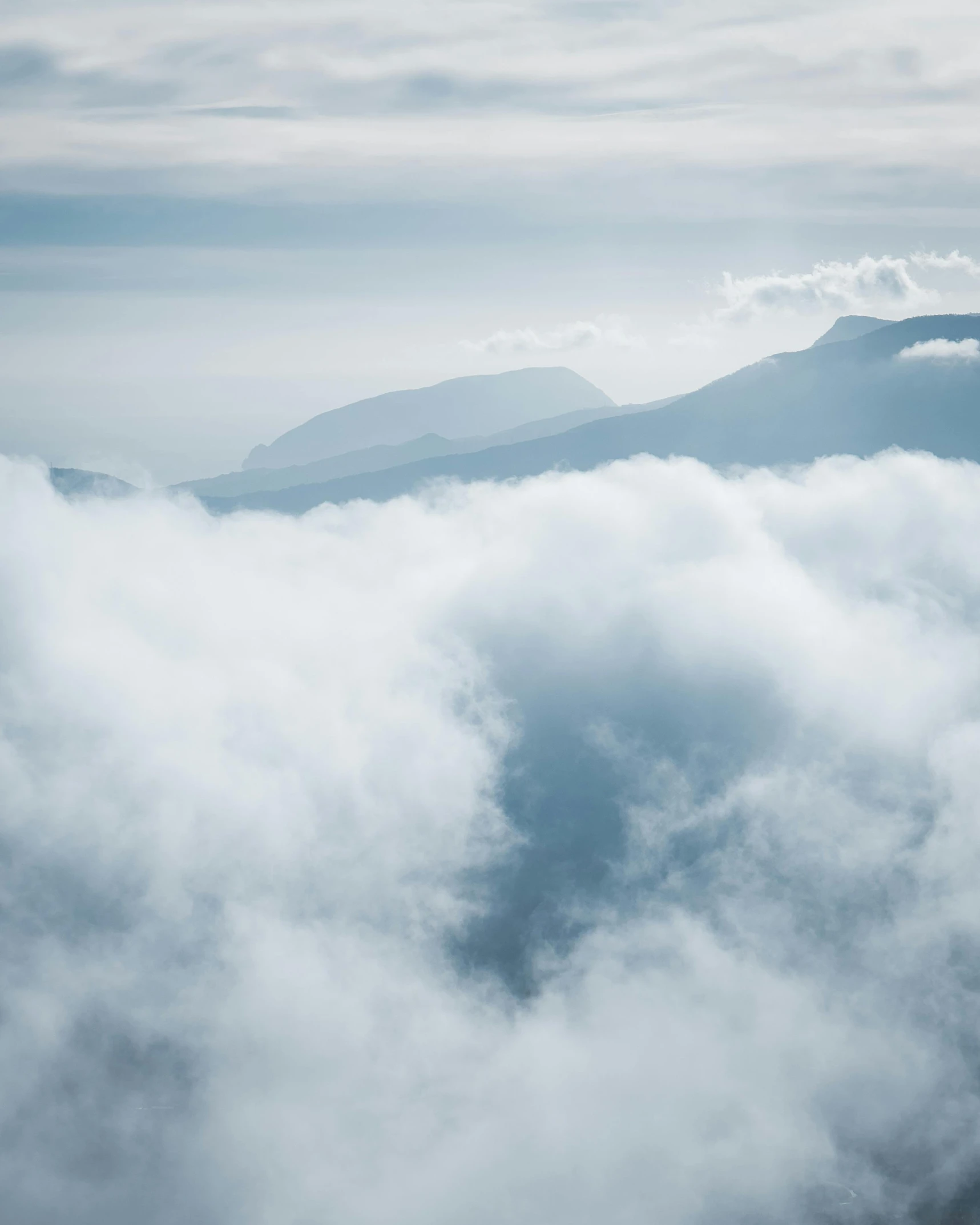 a plane flying through the clouds with a mountain in the background, inspired by Alexander Nasmyth, pexels contest winner, light grey mist, overview, layered fog, cotton candy clouds