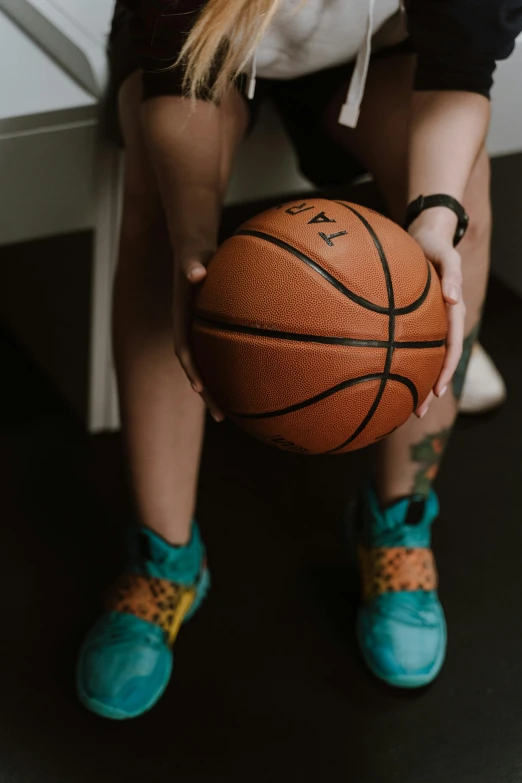 a woman sitting on a desk holding a basketball, inspired by Mia Brownell, trending on dribble, very close up foot shot, teal orange, tattooed, games