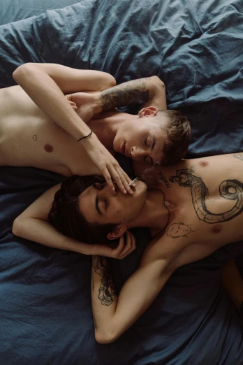 a man and a woman laying on top of a bed, a tattoo, by Jessie Alexandra Dick, trending on pexels, twink, two men hugging, hans bellmer and nadav kander, teen boy