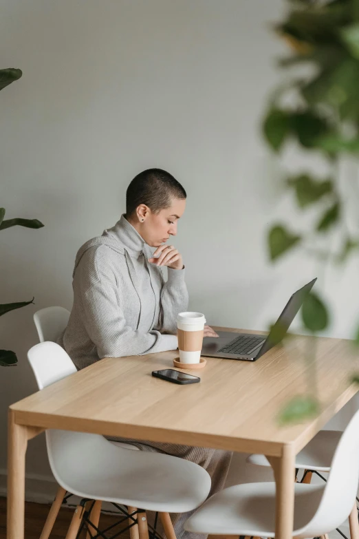 a man sitting at a table with a laptop, trending on pexels, an epic non - binary model, a woman's profile, low quality photo, worried