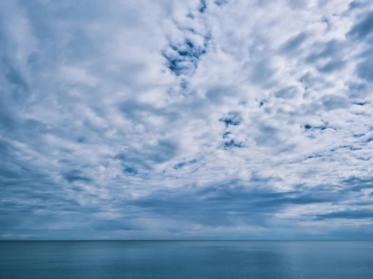 a large body of water under a cloudy sky, unsplash, blue gray, dynamic sky, high-resolution, illustrious