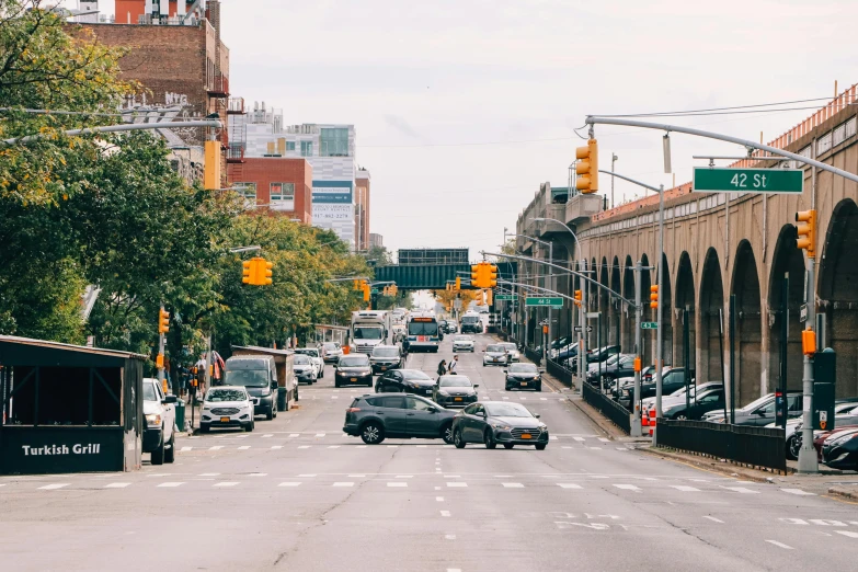 a street filled with lots of traffic next to tall buildings, trending on unsplash, harlem renaissance, lush brooklyn urban landscaping, 2000s photo, fan favorite, cars parked underneath