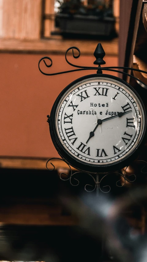 a clock hanging from the side of a building, hotel room, profile image, antiques, black