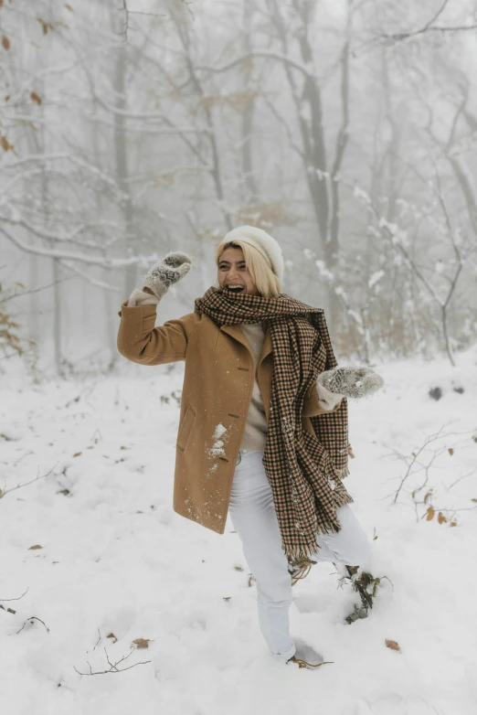 a woman is throwing a frisbee in the snow, pexels contest winner, wearing hay coat, blond, gif, happy fashion model