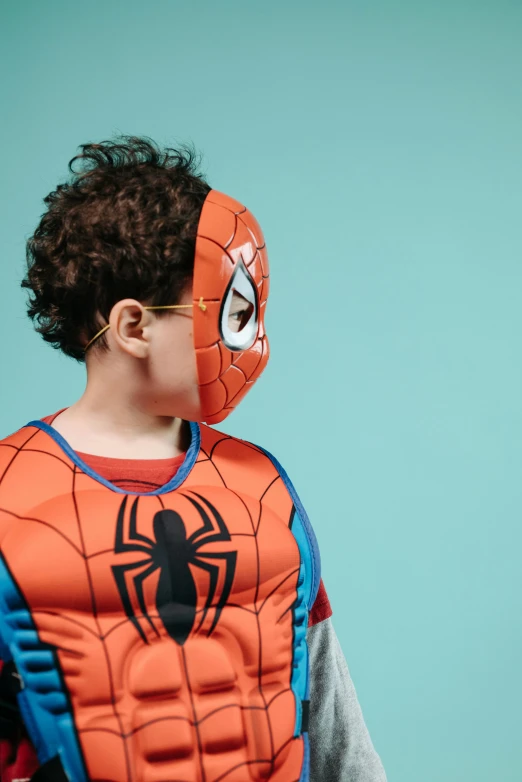 a young boy wearing a spider - man costume, by Paul Bird, pexels, hyperrealism, wearing a mask, blippi, getty images, plain background