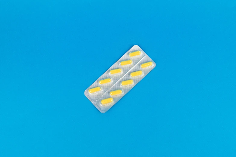 a pill pack sitting on top of a blue surface, by Jan Rustem, plasticien, bolts of bright yellow fish, full body-n 9, smol, nasal strip