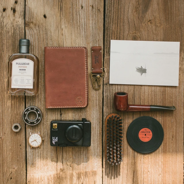 various items laid out on a wooden table, a still life, by Austin English, unsplash, passport, wearing leather, detailed product image, portrait of small