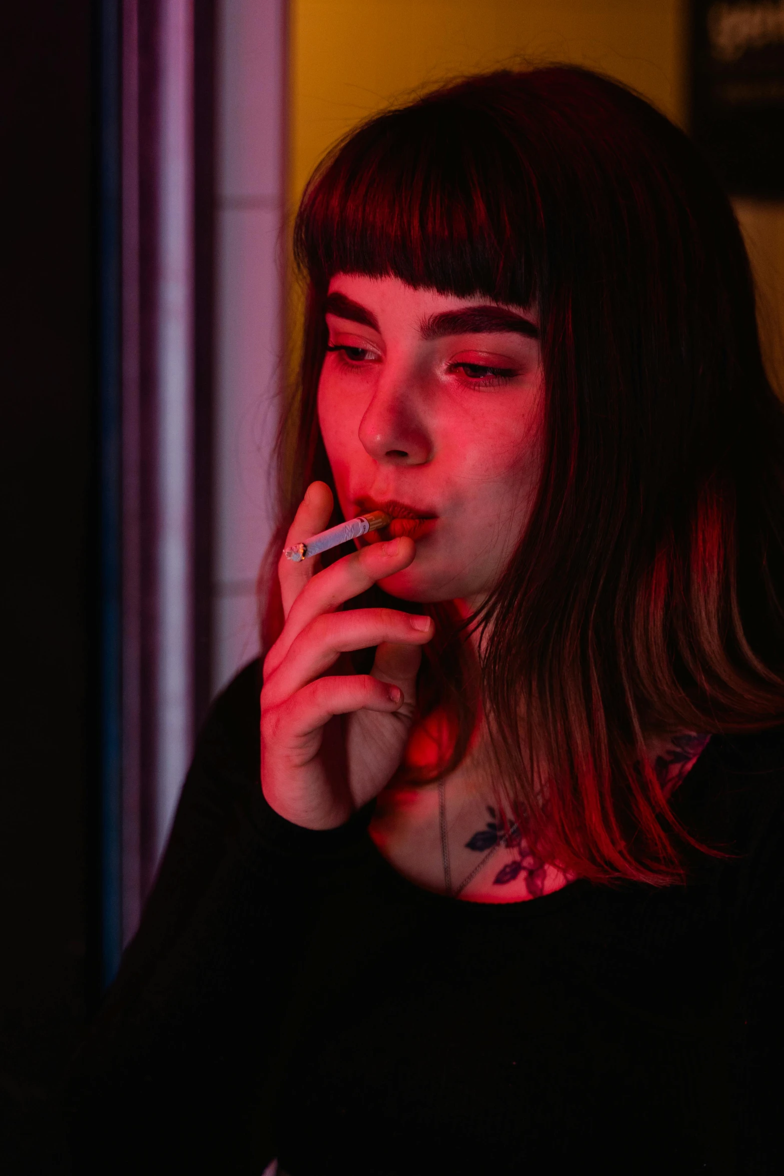 a woman smoking a cigarette in a dark room, inspired by Elsa Bleda, looks a blend of grimes, soft red lights, ((synthwave)), high realism