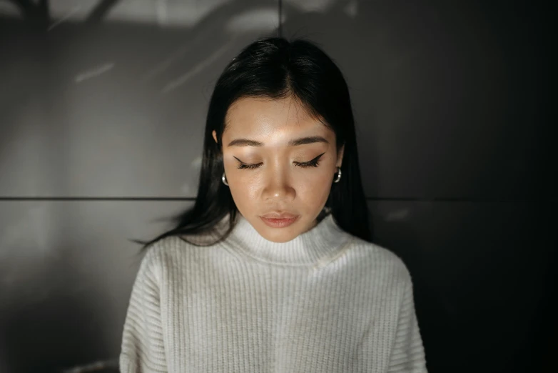 a woman looking down at her cell phone, a character portrait, inspired by Ruth Jên, trending on pexels, hurufiyya, round chin black eyeliner, wearing a white sweater, asian human, with professional lighting