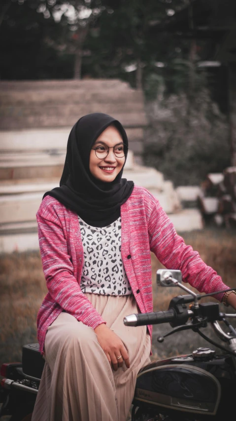 a woman sitting on top of a motorcycle, by Basuki Abdullah, pexels contest winner, realism, wearing a pastel pink hoodie, with square glasses, gif, student