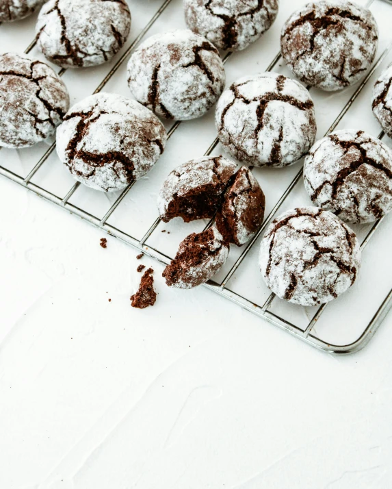 chocolate crinkle cookies cooling on a cooling rack, by Daniel Lieske, pexels, covered in white flour, on a pale background, brunette, made of glazed