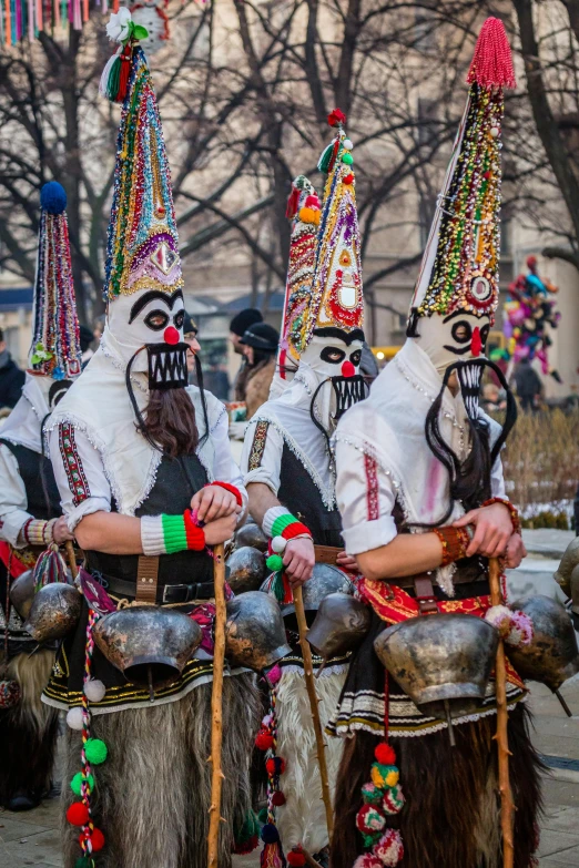 a group of people that are standing in the street, inspired by Bernd Fasching, happening, 3 winter deities, wearing an elaborate helmet, black pulcinella mask, taken in the early 2020s