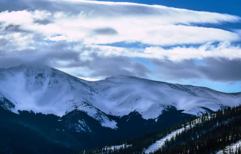 a group of people riding skis down a snow covered slope, majestic clouds, fan favorite, hiking in rocky mountain, album