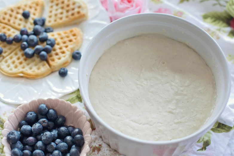 a white bowl filled with blueberries next to waffles, inspired by Christen Købke, background image, silver，ivory, powder, lined in cotton