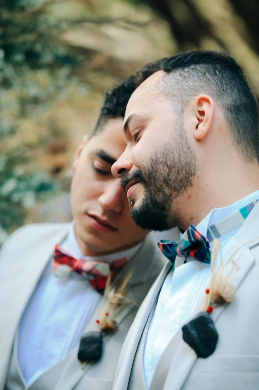 a couple of men standing next to each other, a colorized photo, trending on unsplash, romanticism, bow tie, eyes closed, groom, rustic