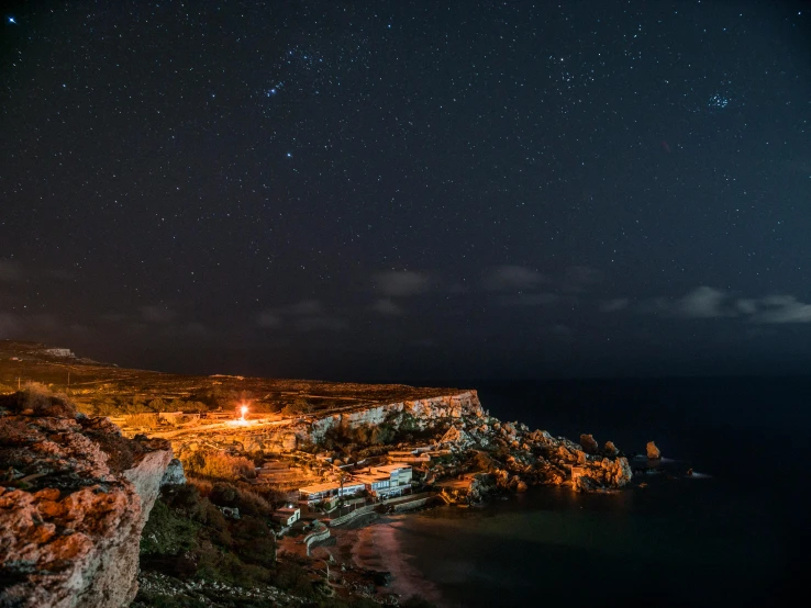 a lighthouse sitting on top of a cliff next to the ocean, pexels contest winner, les nabis, night time australian outback, cyprus, panorama, multiple lights