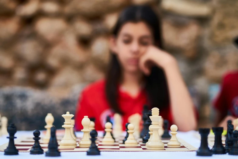 a woman sitting at a table playing a game of chess, unsplash, aged 13, portait image, focus on the foreground, sharp focus »