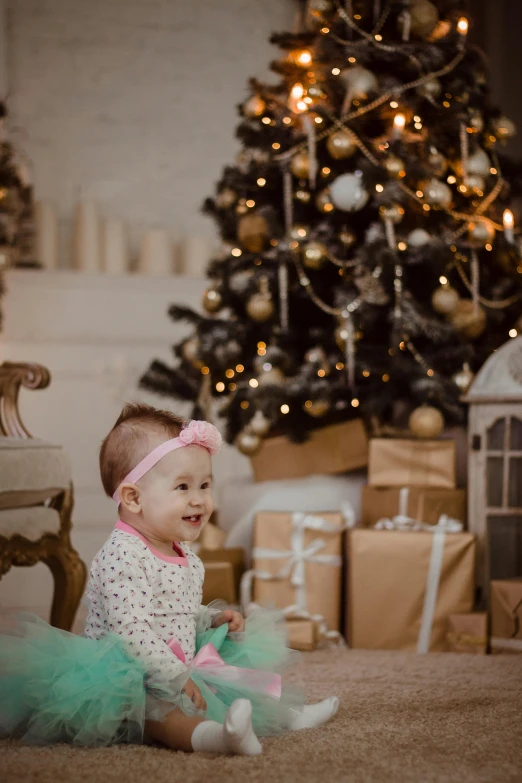a baby girl sitting in front of a christmas tree, pexels contest winner, baroque, shining and happy atmosphere, gif, profile image, small