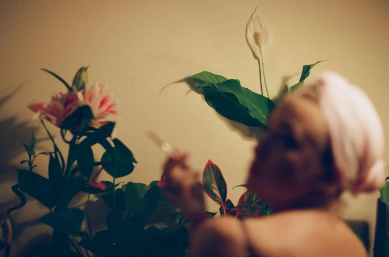 a baby sitting in front of a potted plant, an album cover, inspired by Elsa Bleda, aestheticism, lilies, profile image, lascivious pose, close up photograph