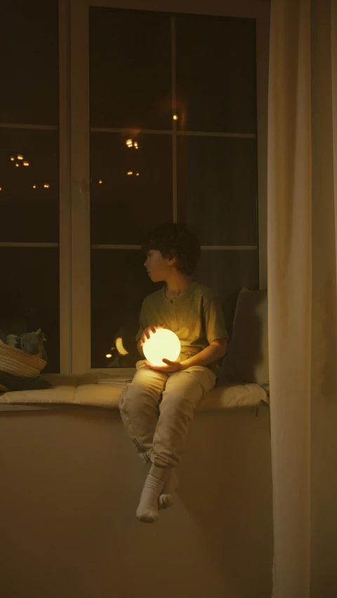 a person sitting on a window sill holding a light, light over boy, light mode, glowing sphere, sitting on couch