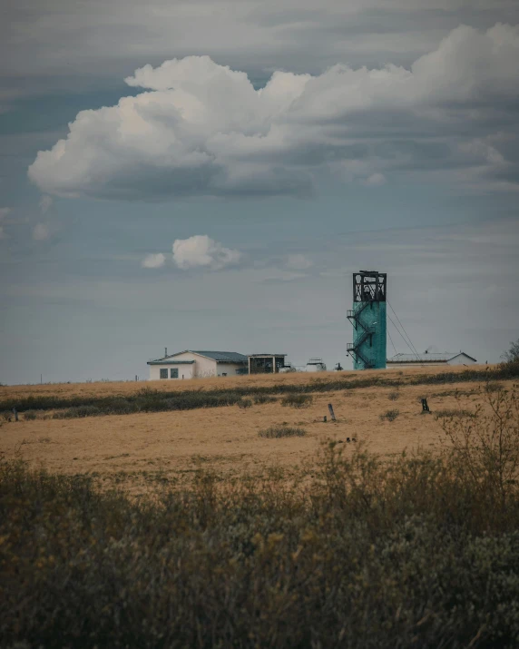 a tall tower sitting on top of a dry grass covered field, a beautiful mine, unsplash photography, stålenhag, multiple stories