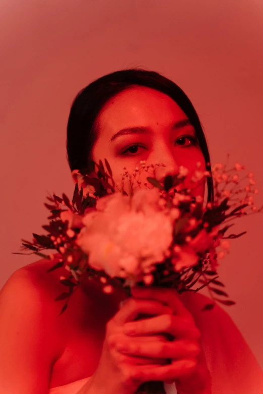 a woman holding a bouquet of flowers in front of her face, an album cover, inspired by Elsa Bleda, unsplash, aestheticism, beautiful asian woman, red monochrome, set on singaporean aesthetic, red glow
