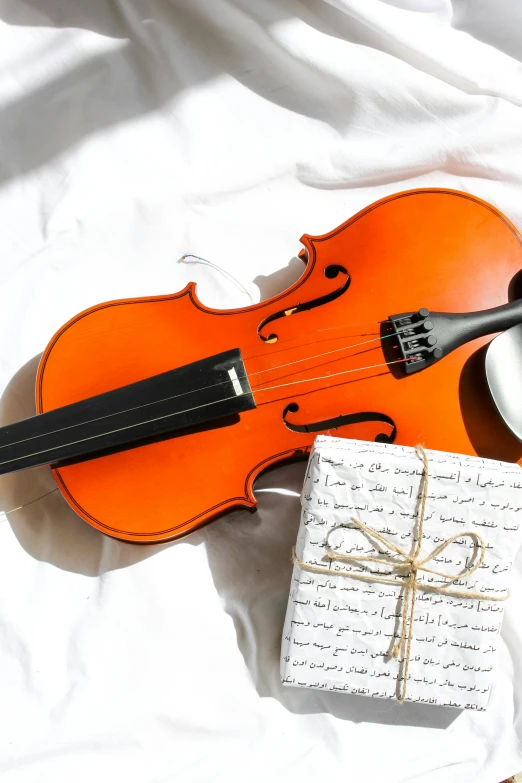 a violin sitting on top of a bed next to a cup of coffee, giving gifts to people, thumbnail, abcdefghijklmnopqrstuvwxyz, white and orange