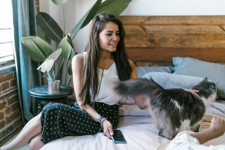 a woman sitting on top of a bed next to a cat, trending on pexels, happening, brunette, talking, profile image, various posed