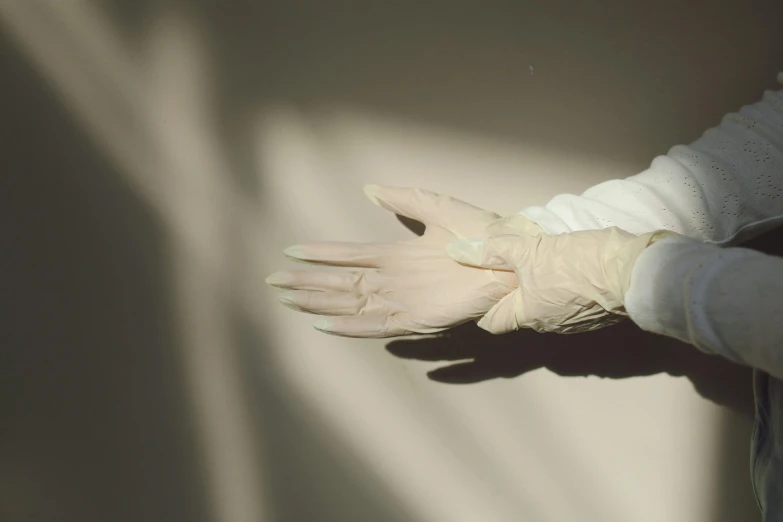 a pair of white gloves sitting on top of a person's arm, unsplash, plasticien, synthetic materials, clinical, faded, jen atkin