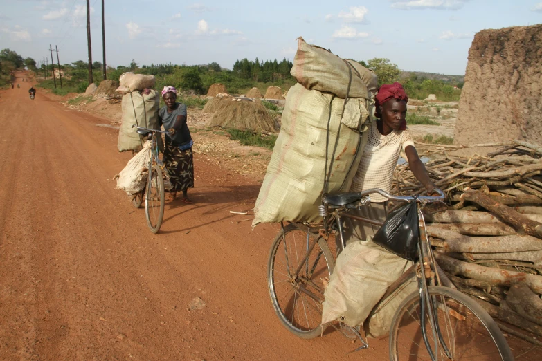 a couple of people riding bikes down a dirt road, hurufiyya, sustainable materials, fleeing merchants, slide show, maintenance photo