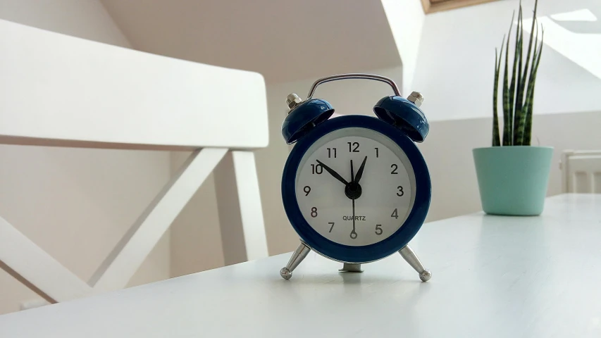 a blue alarm clock sitting on top of a white table, happening, clocktower, looking towards camera, on a table, blue and grey