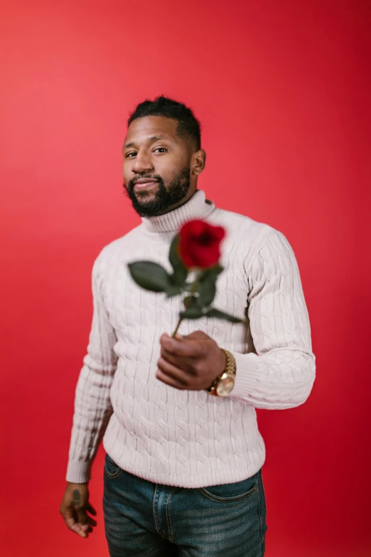 a man with a rose in his hand, an album cover, by Cosmo Alexander, pexels contest winner, mkbhd, red sweater and gray pants, flirtatious, holding a flower