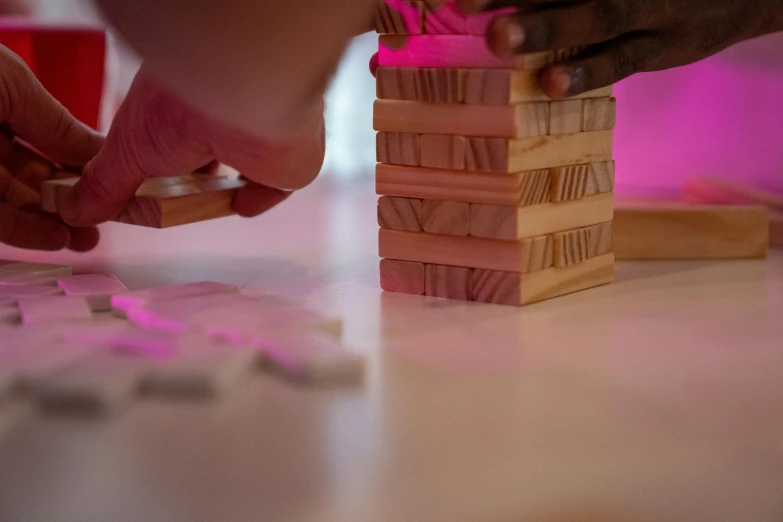 a close up of a person stacking blocks on a table, by Jessie Algie, pink lighting, game, carving, thumbnail