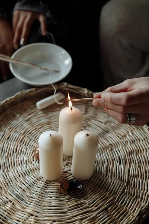 a group of people lighting candles on a wicker tray, a still life, inspired by Kanō Shōsenin, trending on unsplash, white wax, flying rituals, crisp detail, bone and ivory