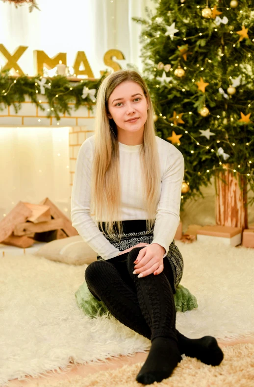 a woman sitting in front of a christmas tree, a picture, by Julia Pishtar, with long blond hair, low quality photo, teenager, background image