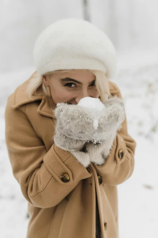 a woman standing in the snow wearing a coat and mittens, a photo, trending on pexels, square, fluffy face, tan, gif