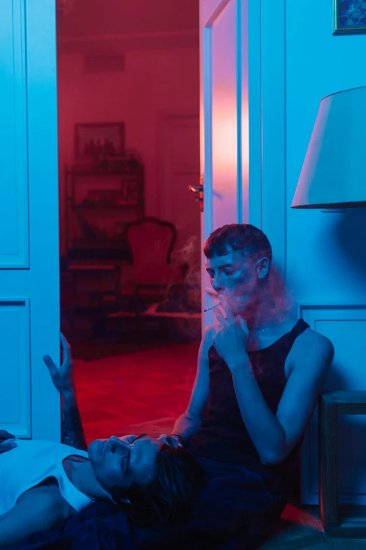 a person sitting on the floor in a room, inspired by Nan Goldin, muted neon smoke, vitalik buterin, sitting in french apartment, blue and red lighting