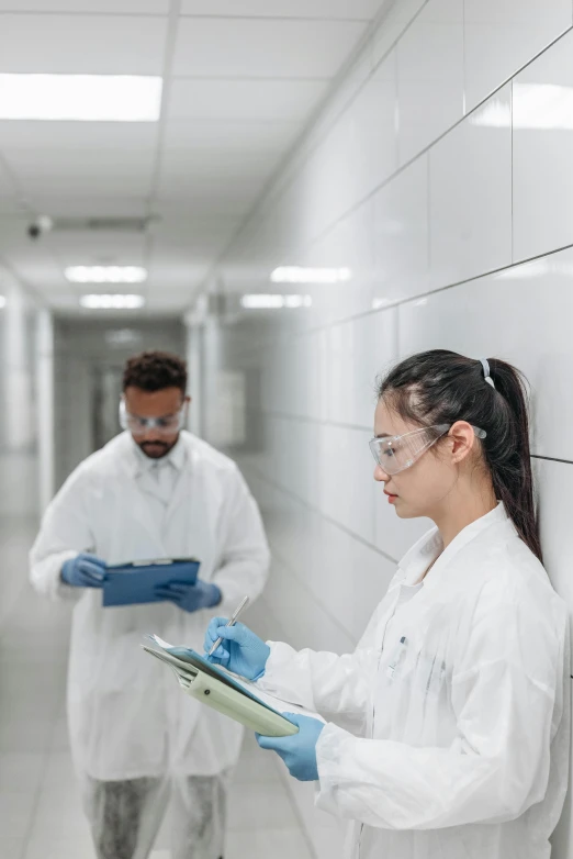 a couple of people that are standing in a hallway, working in her science lab, holding a clipboard, 2019 trending photo, thumbnail