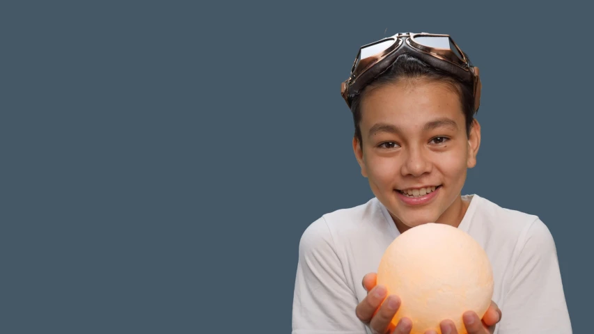 a close up of a person holding an egg, wearing goggles, light over boy, darren quach, orange light