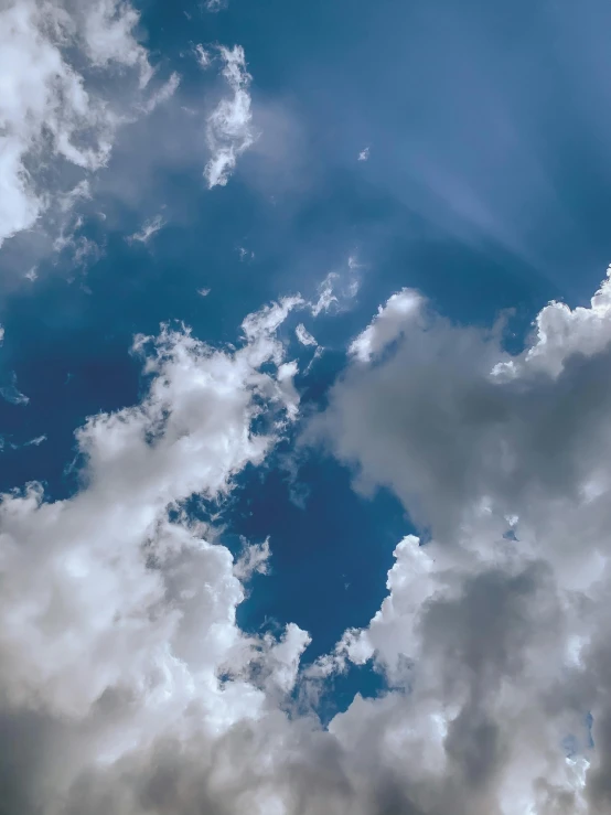 a plane flying through a cloudy blue sky, an album cover, by Niko Henrichon, unsplash contest winner, light and space, ☁🌪🌙👩🏾, puffy cute clouds, today\'s featured photograph 4k, highly accurate