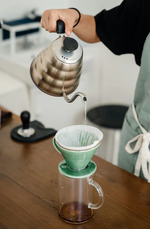 a person pouring water into a coffee pot, inspired by Kinichiro Ishikawa, trending on unsplash, cone shaped, green, enamel, bone