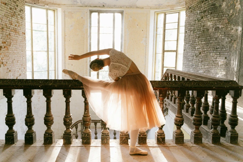 a woman in a tutu is standing on a railing, by Elizabeth Polunin, pexels contest winner, arabesque, in a castle, in shades of peach, dance scene, inspired in balthus